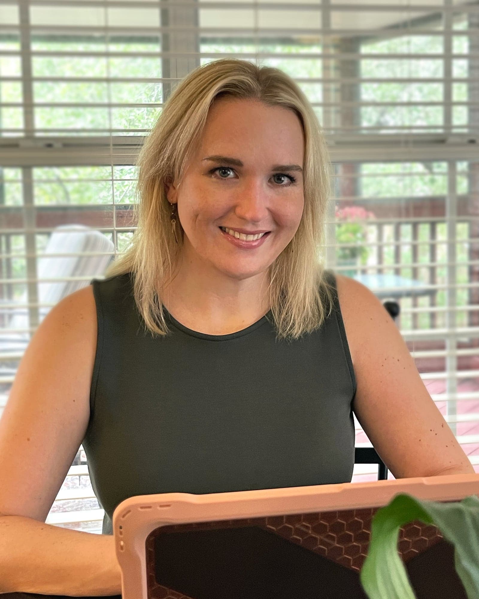 Anne Schmidt smiling at her laptop on a screened porch